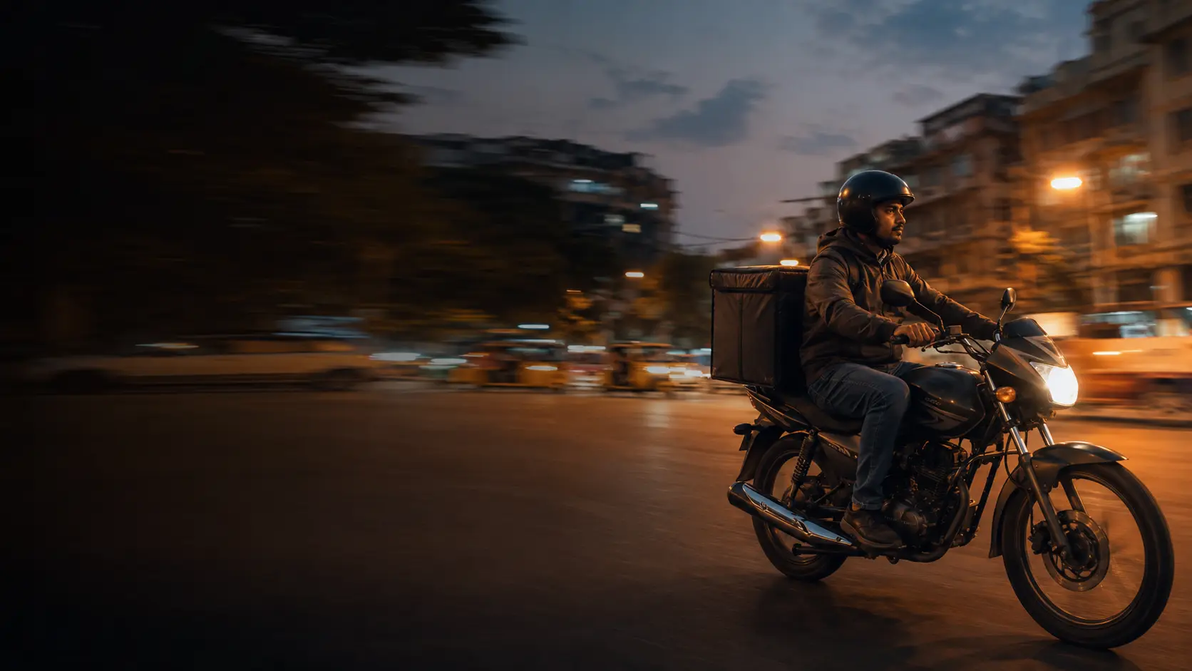 Delivery rider on a motorcycle in Hyderabad traffic at dusk, gig worker health and accident care at Vivekananda Hospital Begumpet